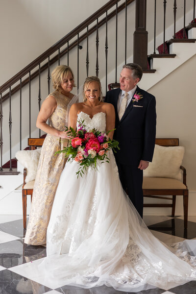 A bride standing between her parents during formal family photos at Hazelenut Farms. 