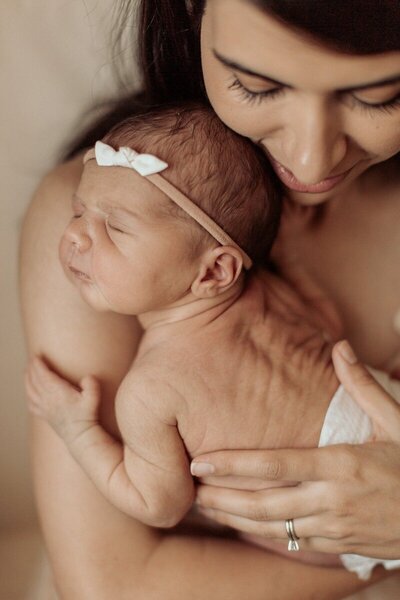 Mother cuddling newborn baby girl captured by Michigan photographers