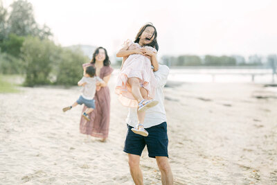 Sydney dad plays with toddler during golden hour beach session—natural family photography capturing joy in motion