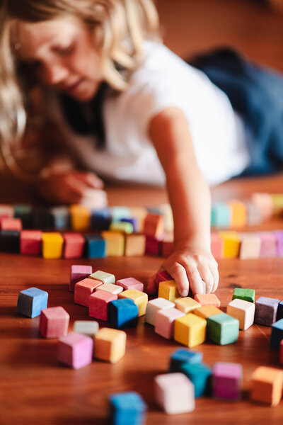 Mila dans l'atelier de Paul Teneze jouant avec des cubes de couleur.
