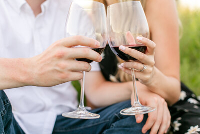 A set of two hands holding red wine glasses.