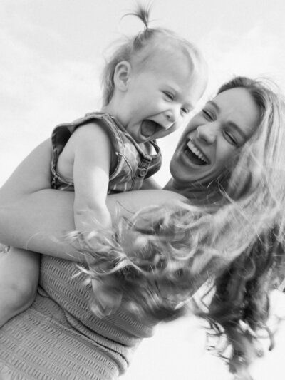 Black and white image of a mom holding her child and laughing