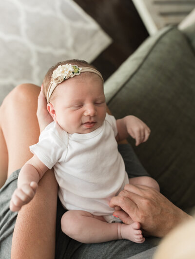 newborn baby girl laying in mom's lap for in home session