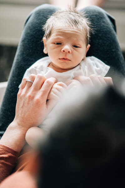 A tiny baby lies in his crib on his tummy wearing his newborn size diaper.