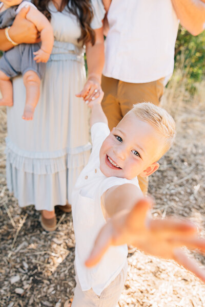 A young boy reaches his hand toward the camera. Neutral colors for family photos in Memphis, Tennessee.