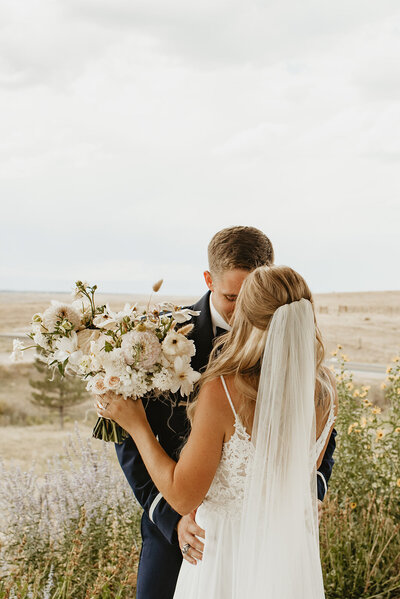 Bride facing the groom while holding her floral bouquet in a beautiful outdoor area