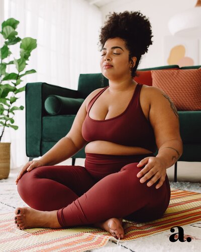 An image of a curvy woman doing yoga in a very stylish apartment.