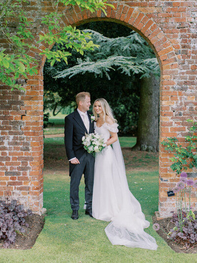 bride and groom natural and relaxed portrait with red brick arch behind