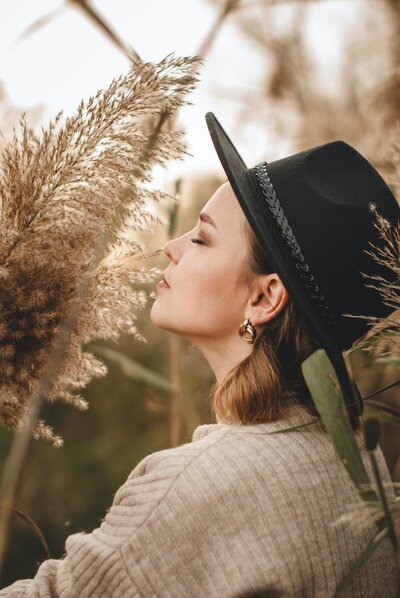 woman with a black hat standing in a fiel of dried grasses