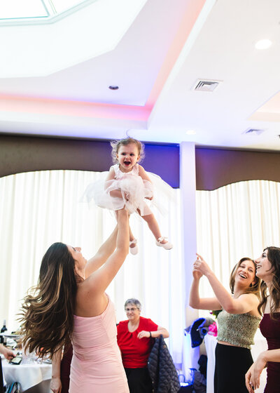 Mom holding laughing daughter in air at a NJ birthday party.