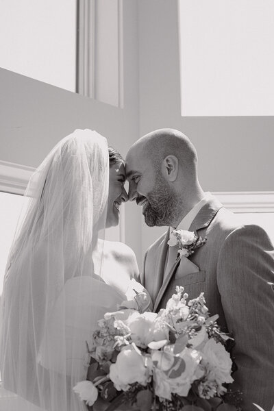 Couple on their wedding day leaning against their foreheads