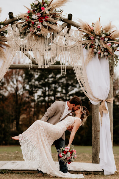 boho wedding decor at little rock wedding venue with groom dipping his bride backwards as he kisses her and holds her leg up