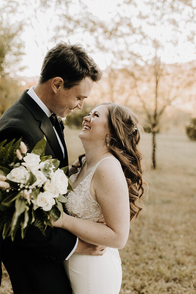 Bride and groom embracing and looking up, smiling at each other