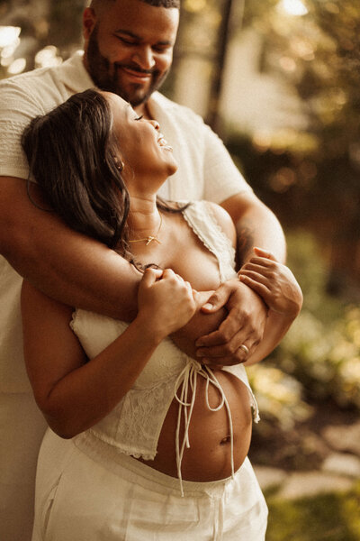 Pregnant woman cradling baby bump during golden hour maternity session in Nashville