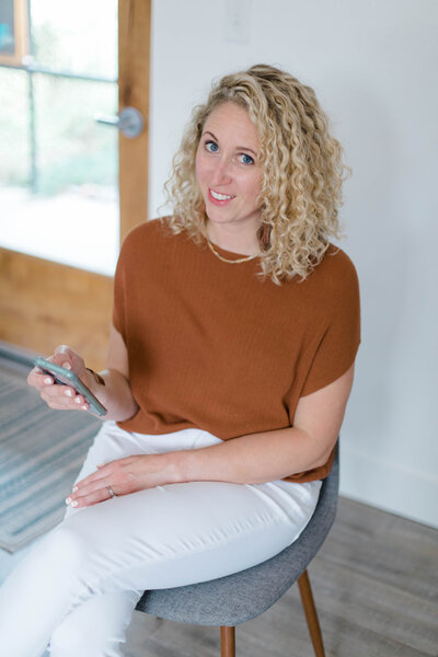 Lauren Haug Northern Colorado Real Estate Agent holding her iPhone and smiling