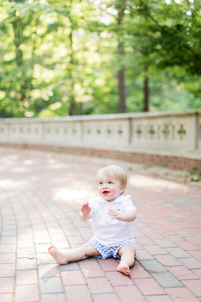 Adorable toddler boy on a brick path happy and smiling for his Richmond family photographer