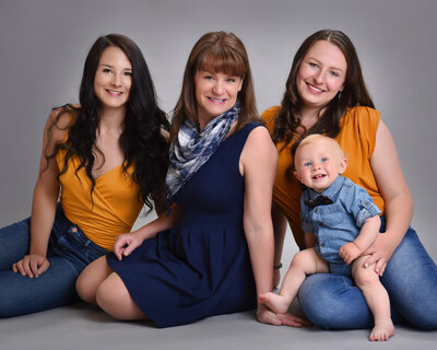 mom with daughters and grandson studio portrait sitting on floor