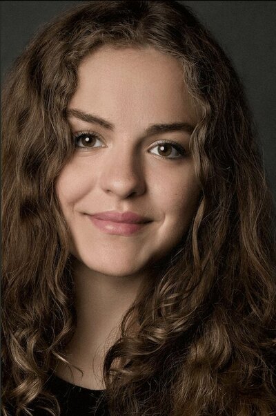 woman leaning against a granite wall smiling at the camera for a business portrait