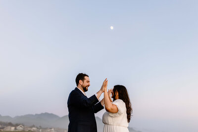 couple high fiving in blue hour with moon