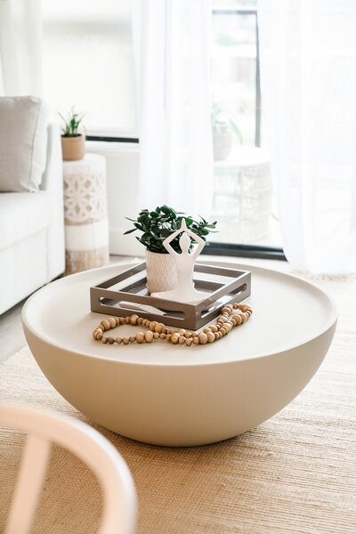 Modern living room with round wood coffee table and tabletop decor.