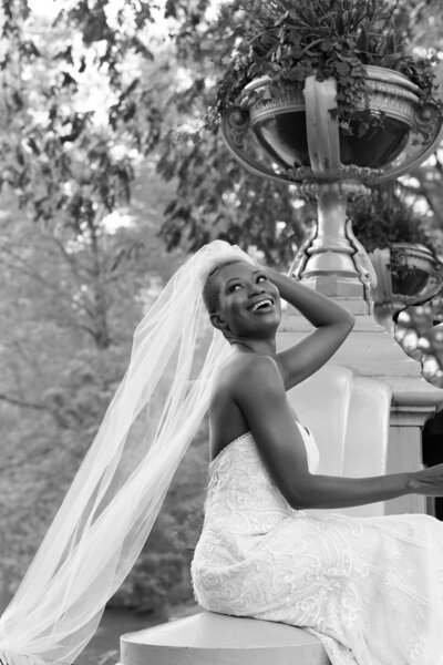 Elegant happy black bride with veil and Maggie Sottero wedding dress at Central Park's Bow's Bridge.
