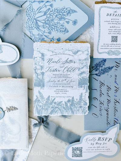 dusty blue wedding invitation with calligraphy and fun shape