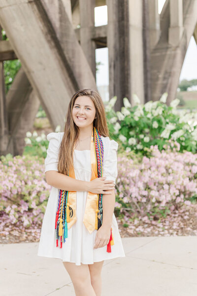 High school senior smiles while wearing graduation cords