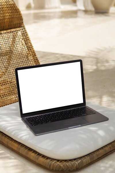 Amare Mockup Shop: MacBook mockup gracefully positioned on a beech chair in a boho-style environment, merging modern technology with rustic charm.