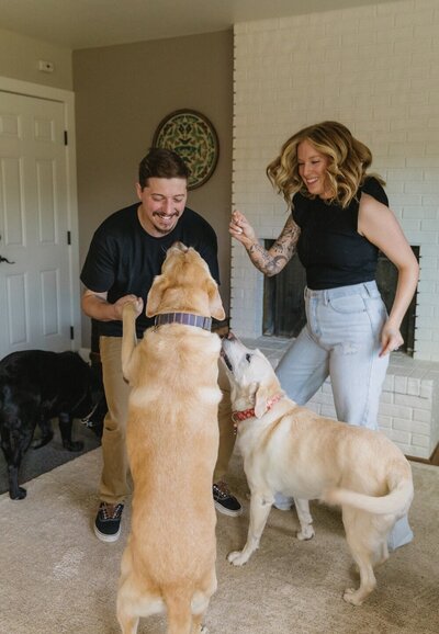 In home lifestyle engagement session where couple is dancing with their dogs in the living room