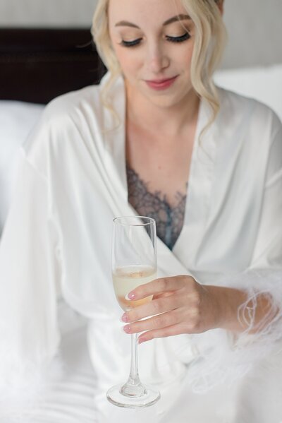 Bride holding champagne while getting ready for wedding at Athletic Club of Columbus