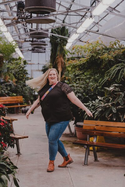 The owner of Bore Tide Photography spins around in the middle of a local greenhouse