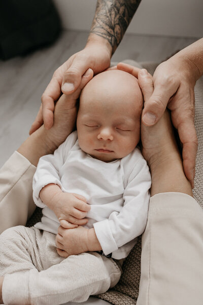 Baby ligt te slapen in de armen van mama en papa