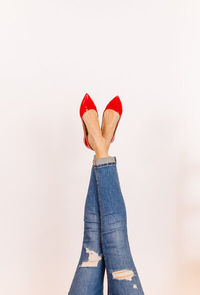 women's legs with jeans and flat shinny red shoes centered in a portrait framed picture
