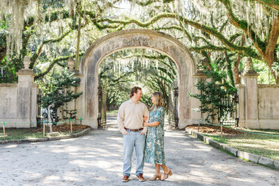 an engaged couple posing near hanging moss trees