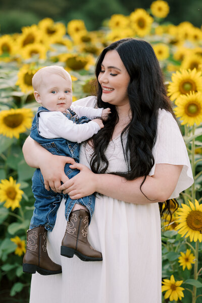 Mom and baby posing for the camera in front of sunflowers