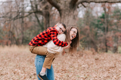 An older child grabbing a piggyback ride from his mom