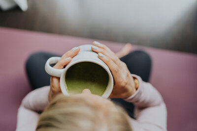 Aerial view of a women taking a sip of matcha in a white coffee mug