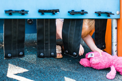 kid with plush bunny climb under toy at playground