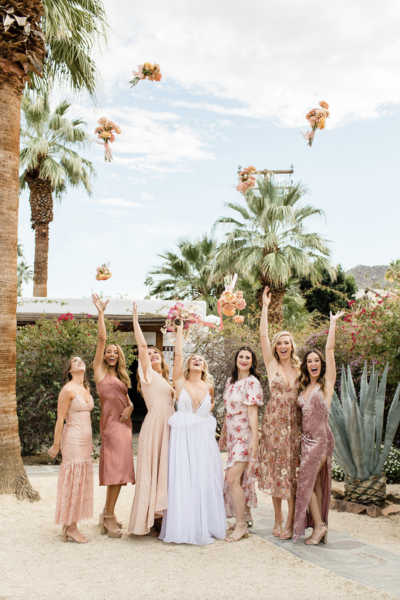 Bride and bridesmaid throwing bouquets up in the air. Photo taken by Cheers Babe Photo and edited by RAW Digital Lab.