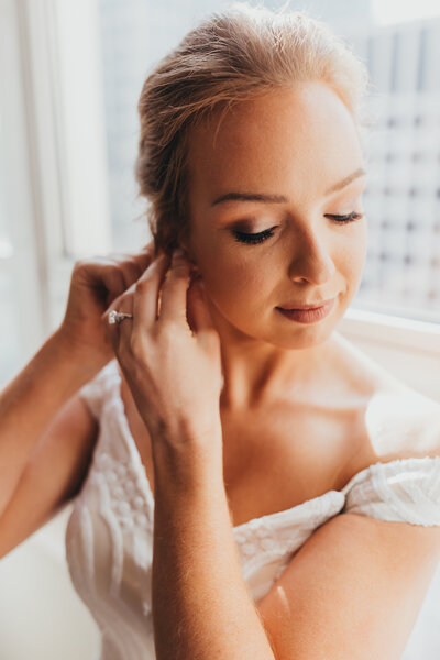 Wedding photo of bride getting ready putting on earrings