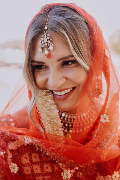 A bride wearing a red sari smiles gently