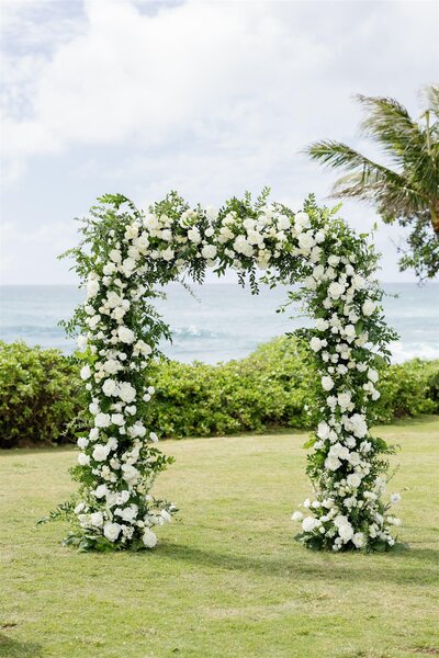 A wedding arch covered in white and green florals 