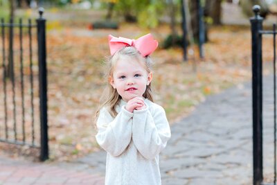 A little girl with pink hair bow poses for a family photography session in Conway Arkansas.