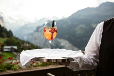 Aperol Spritz served on a private terrace at a luxury chalet in the Swiss Alps with panoramic mountain views.”