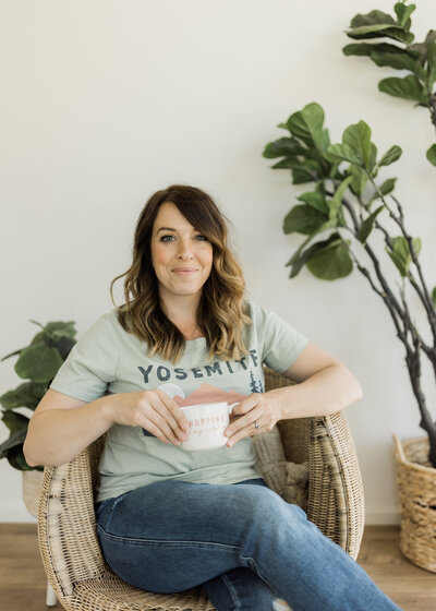 My Design Assistant's founder, Brittanie Elms, sitting in a chair holding a coffee cup
