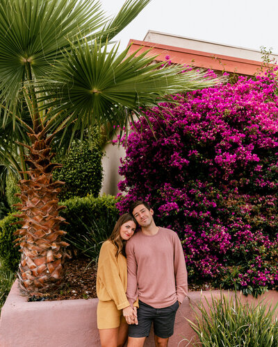 man and woman standing by flowers smiling