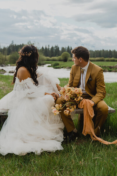 The bride and groom sit quietly on a bench, taking in the breathtaking mountain views of Central Oregon—wrapped in the peaceful beauty of their first moments as newlyweds.