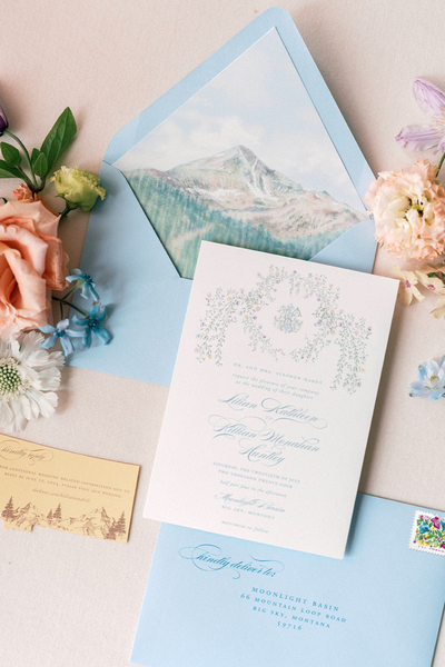 Pastel wedding invitation suite for a Moonlight Basin wedding, featuring a floral monogram, Montana die-cut card, and watercolor Lone Mountain liner.