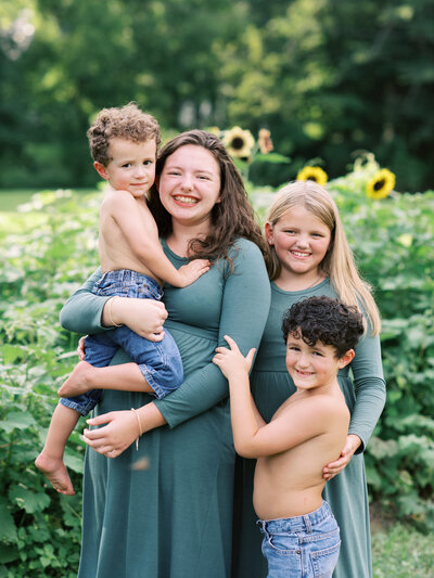 Four kids posing for the camera in front of sunflowers