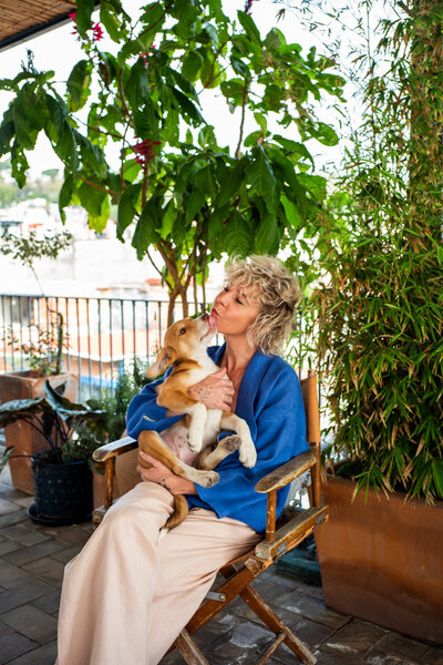 Dog behavior specialist, Sasha Armstrong, sitting in chair getting puppy kisses